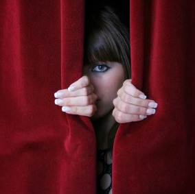 Woman peeping through a red curtain